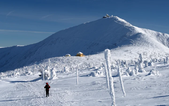 蓝天下的积雪山峰、雪原和山间小屋构成宁静的冬季风景。