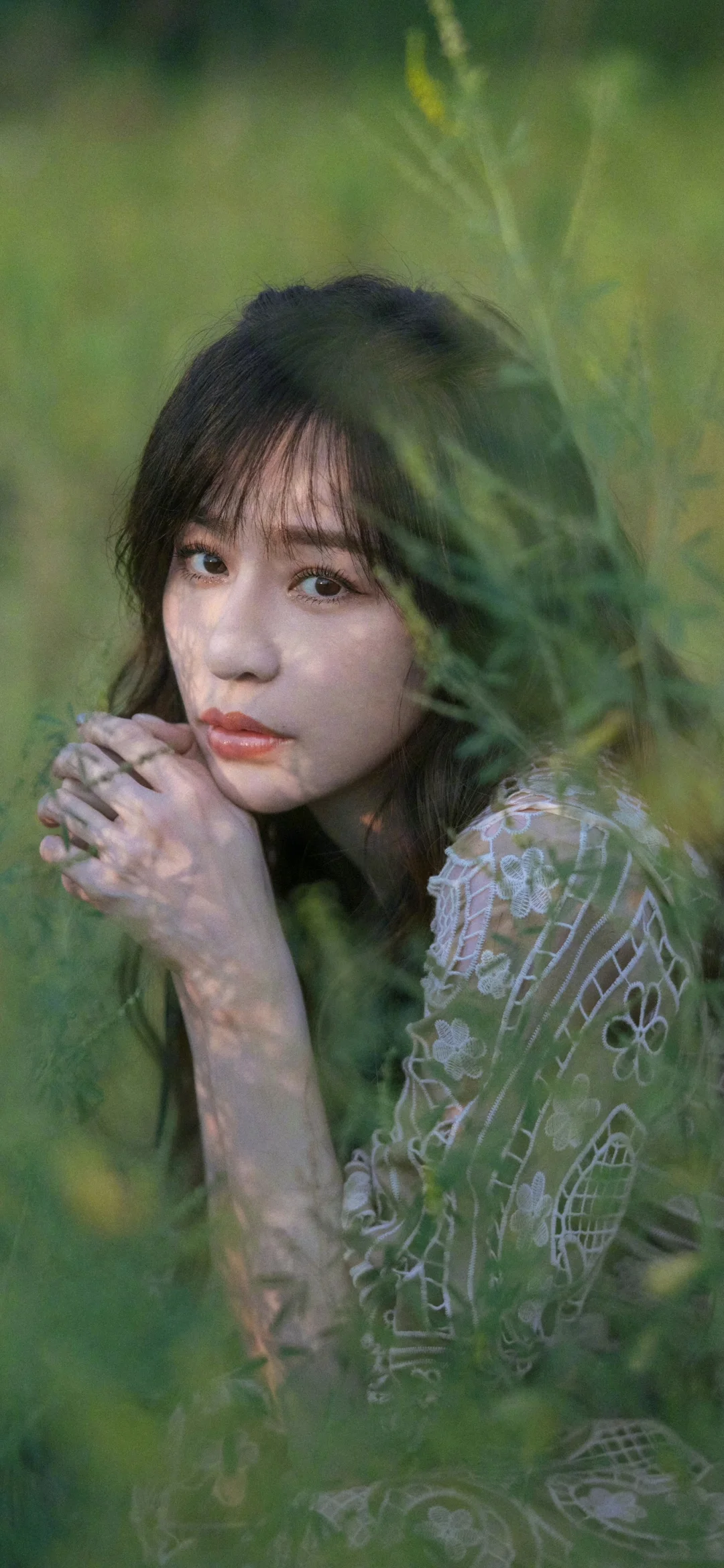 초록 잎사귀 사이로 성인 여성이 레이스 상의를 입고 자연스러운 인물 구도를 이루고 있습니다.