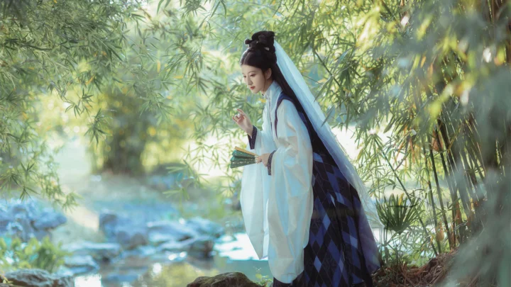 一名身穿浅色古装的女子站在竹林溪流旁。