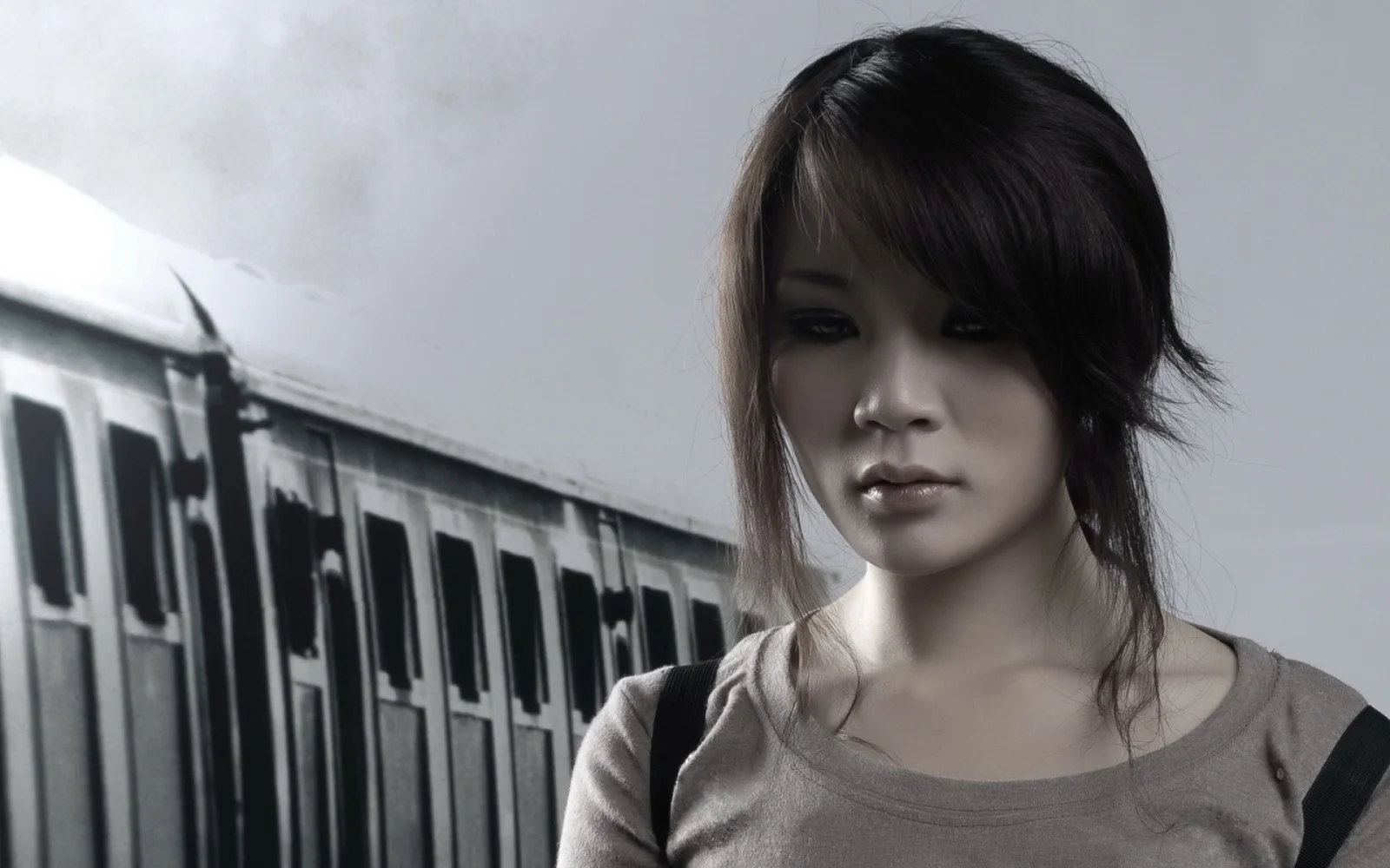 列車を背景にした黒髪の女性のモノクロポートレート。