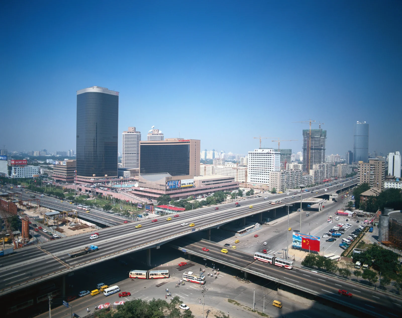 晴朗蓝天下，城市高楼、立交桥和繁忙道路构成开阔的城市景观。