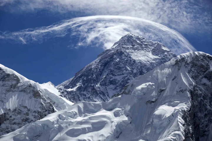 巍峨的雪山与冰川在蓝天和环绕的云层下延展开来。