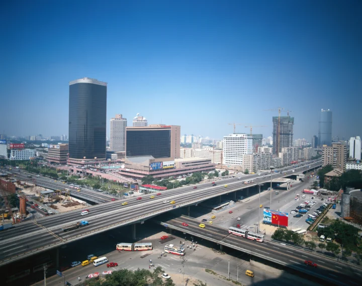 晴朗蓝天下，城市高楼、立交桥和繁忙道路构成开阔的城市景观。