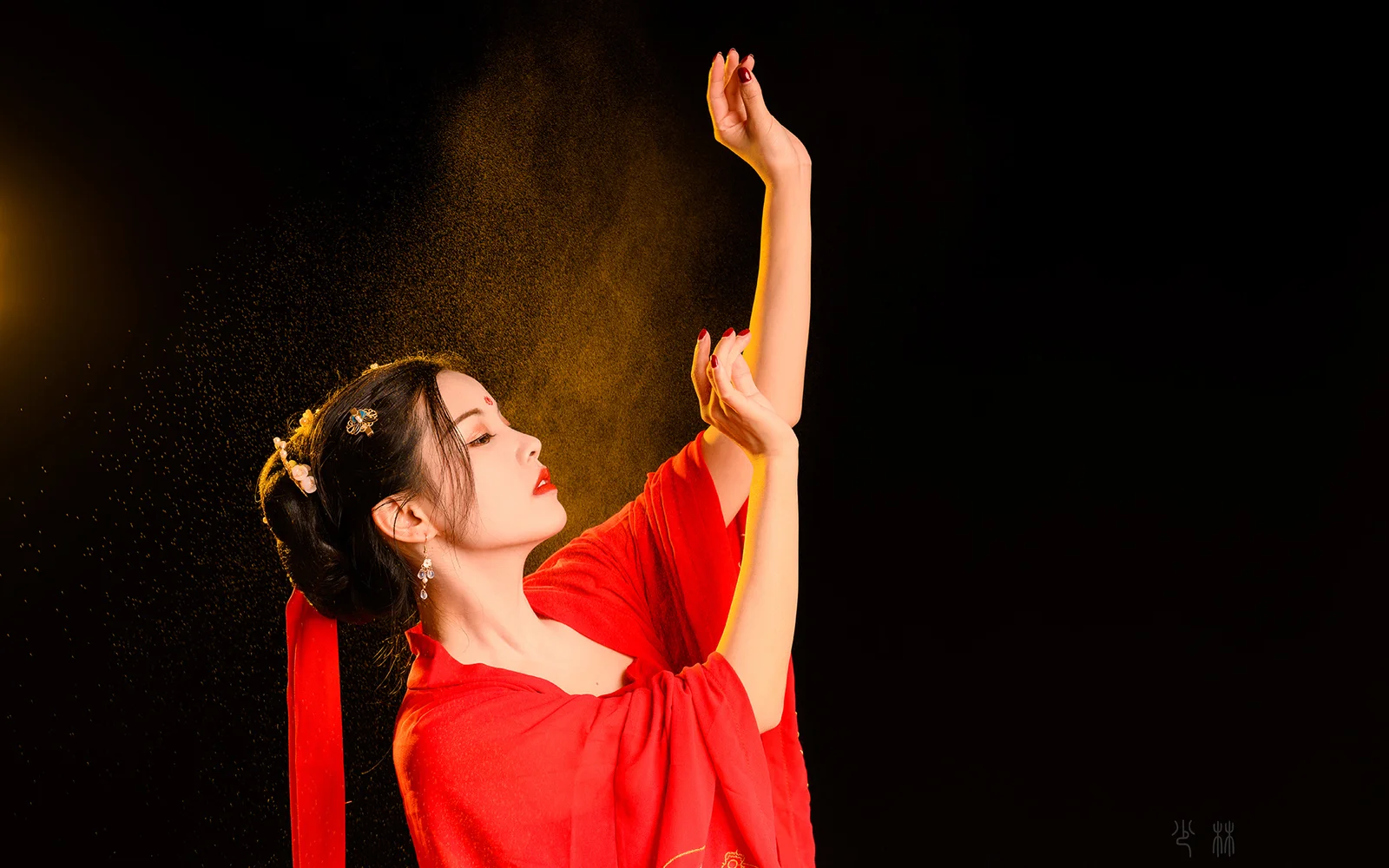 一名身穿红色服装的女子在黑色背景前抬起双臂。