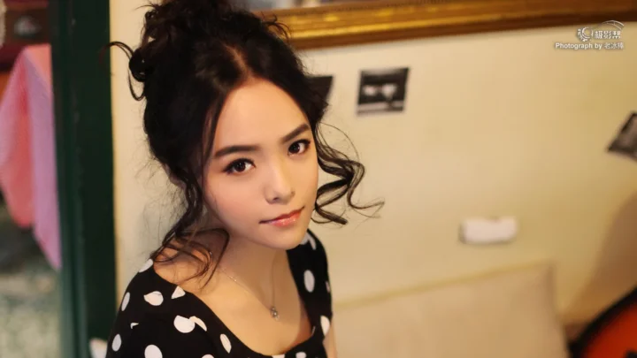一名成年女性身穿黑白波点连衣裙，在室内面对镜头微笑。
