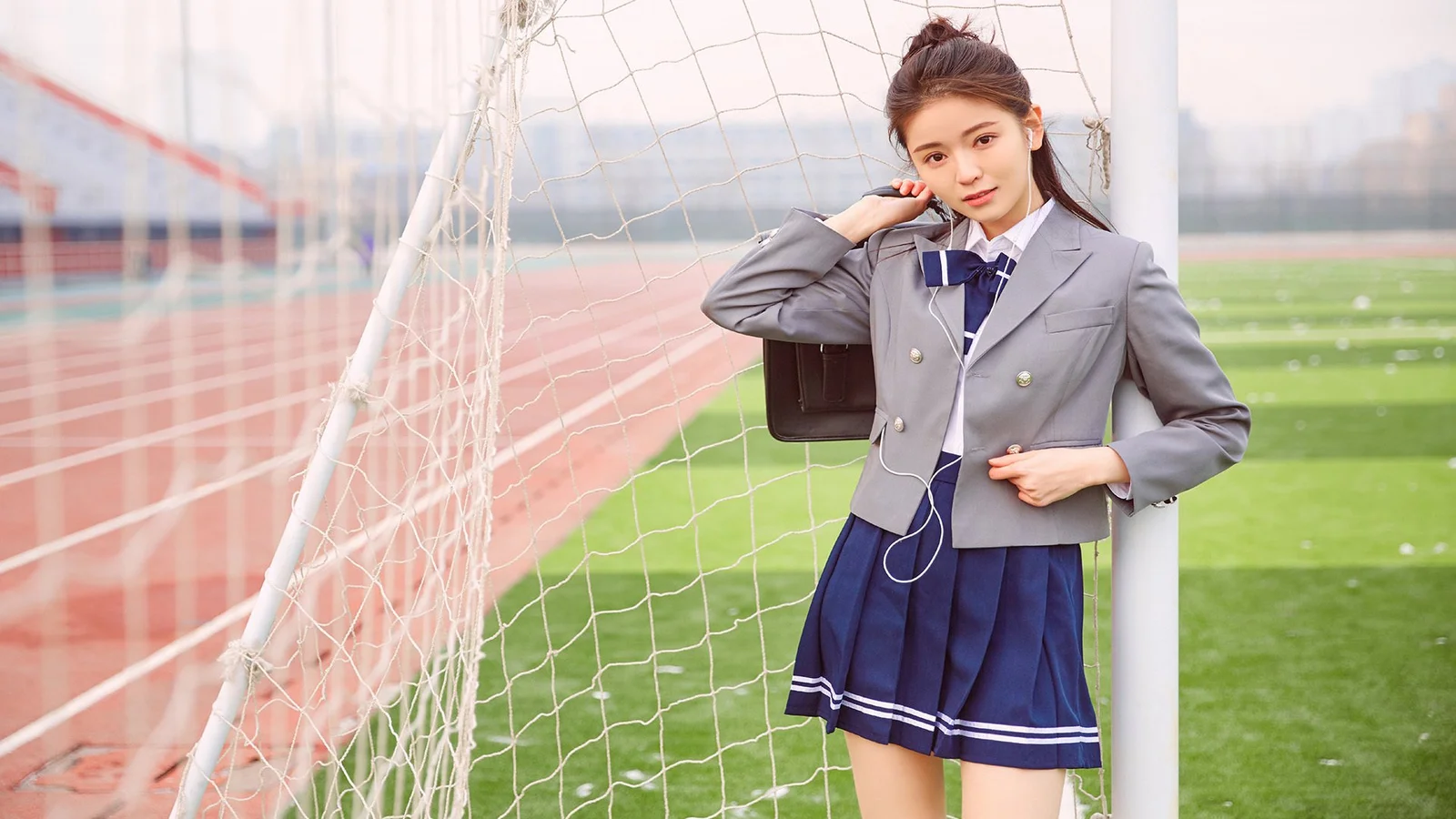 一名身穿灰色制服的女性站在足球场球门旁。