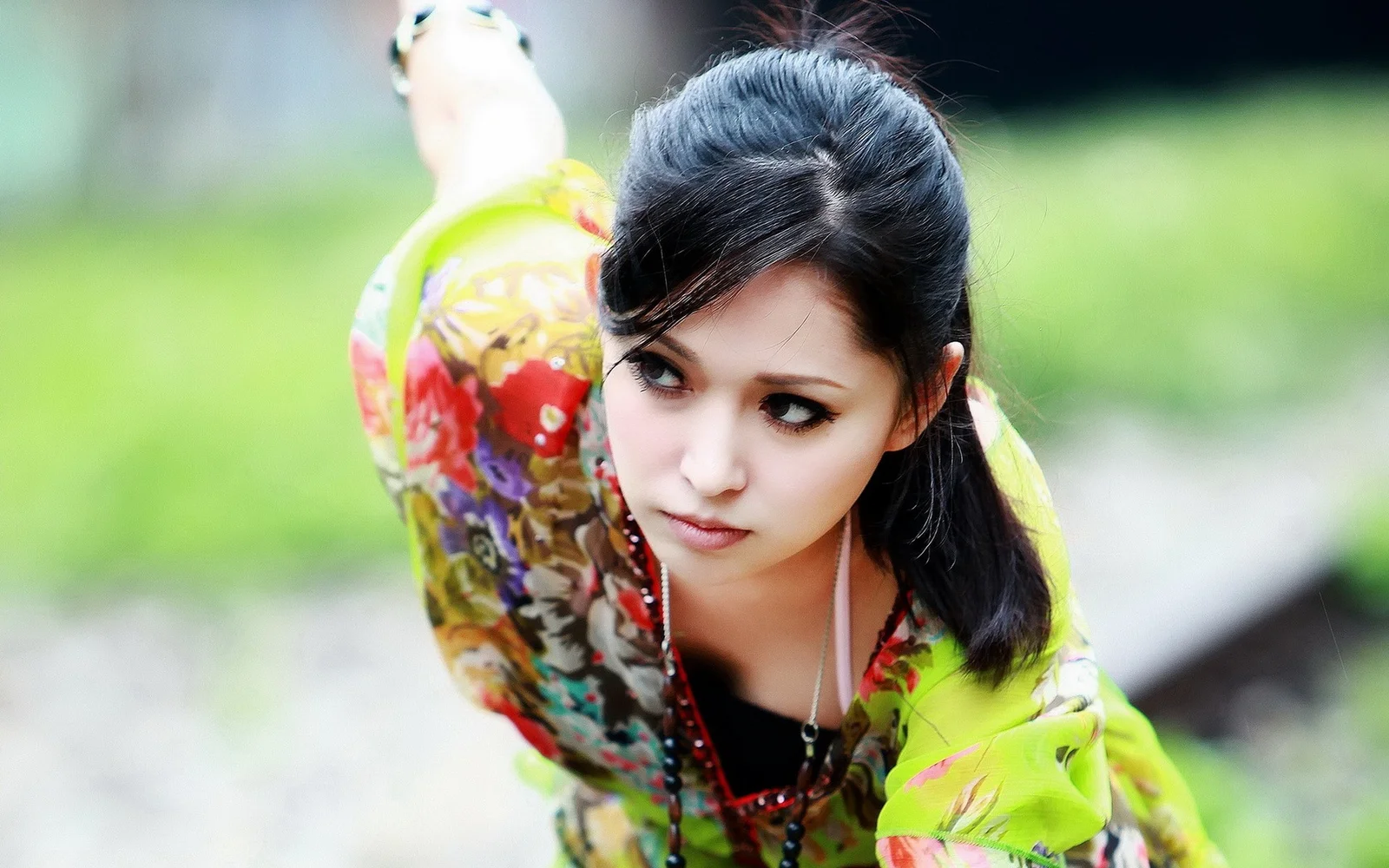 一名身穿彩色服装的成年女子在户外近距离望向镜头。