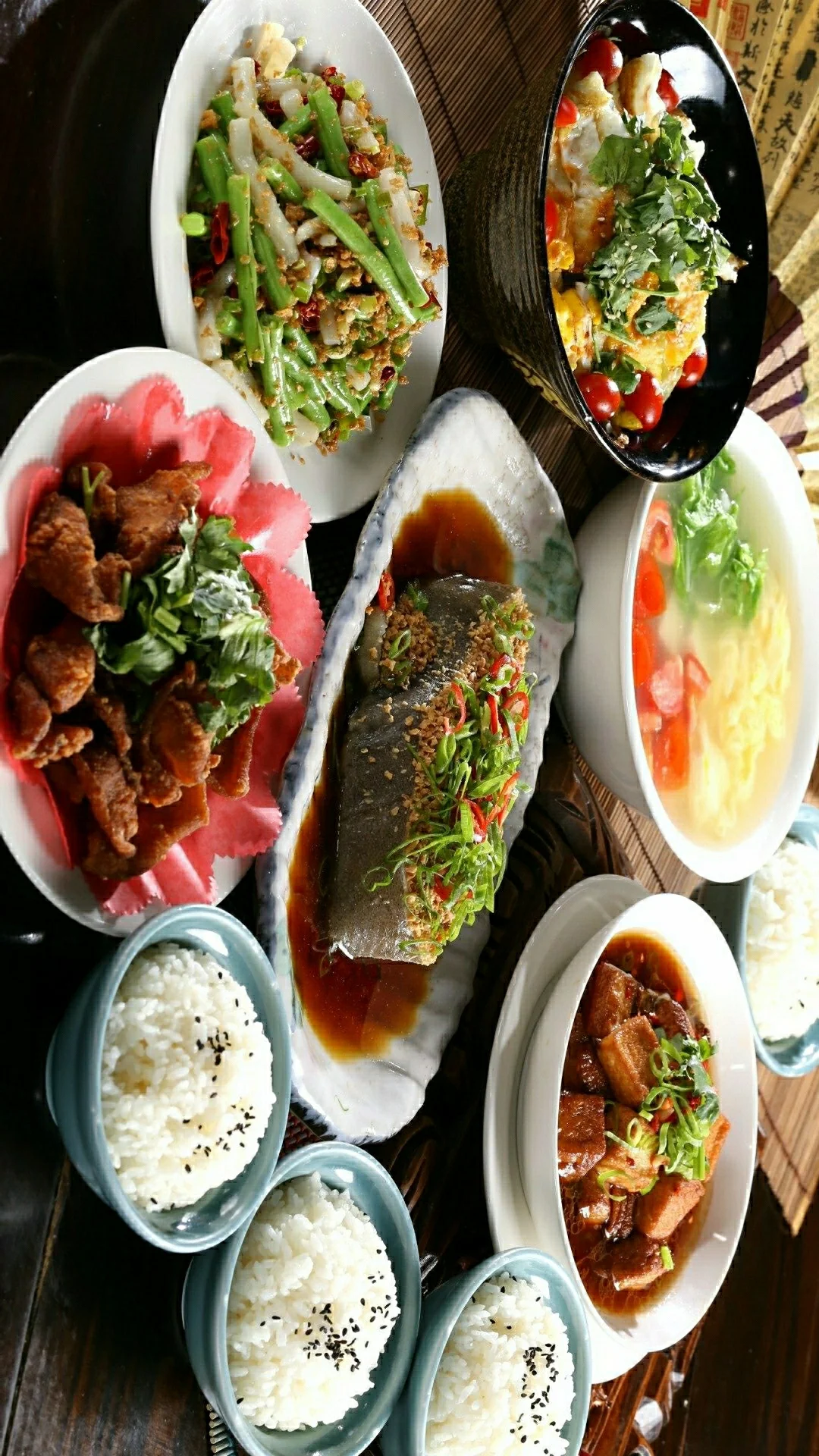 俯拍一桌摆放着鱼、米饭、肉类和蔬菜的中式菜肴。