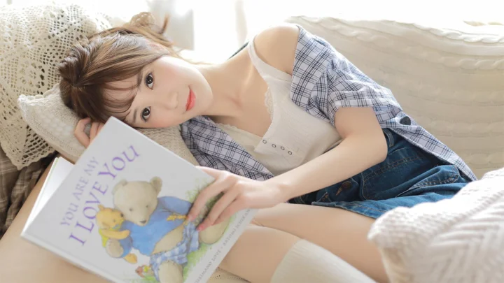 一名成年女子躺在床上阅读一本绘本，画面光线明亮柔和。