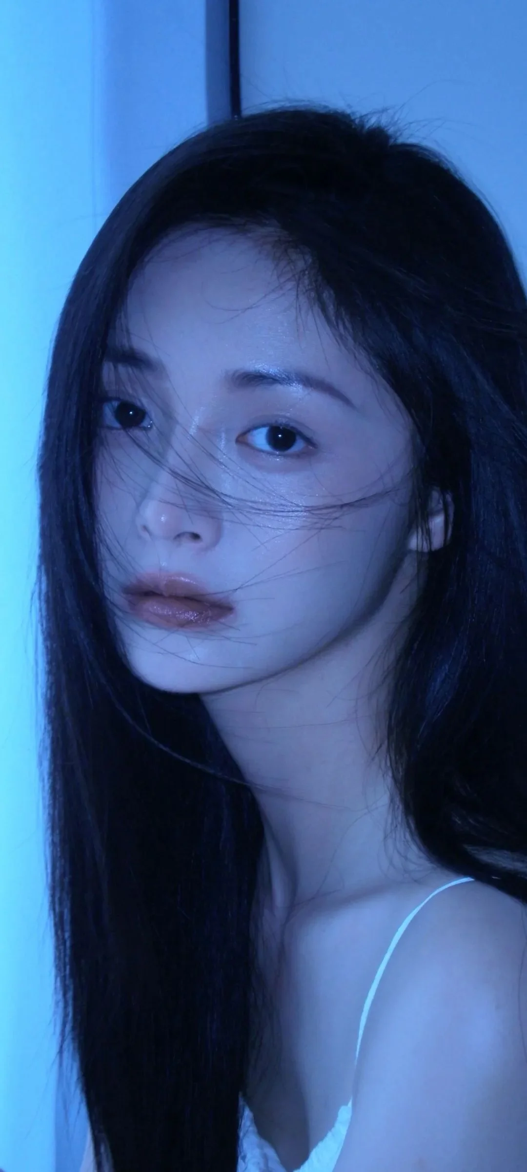 一位长发女性在蓝色光线下的近距离人像照片。