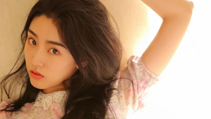 一名长发女子穿着浅色碎花上衣，抬起手臂看向镜头。