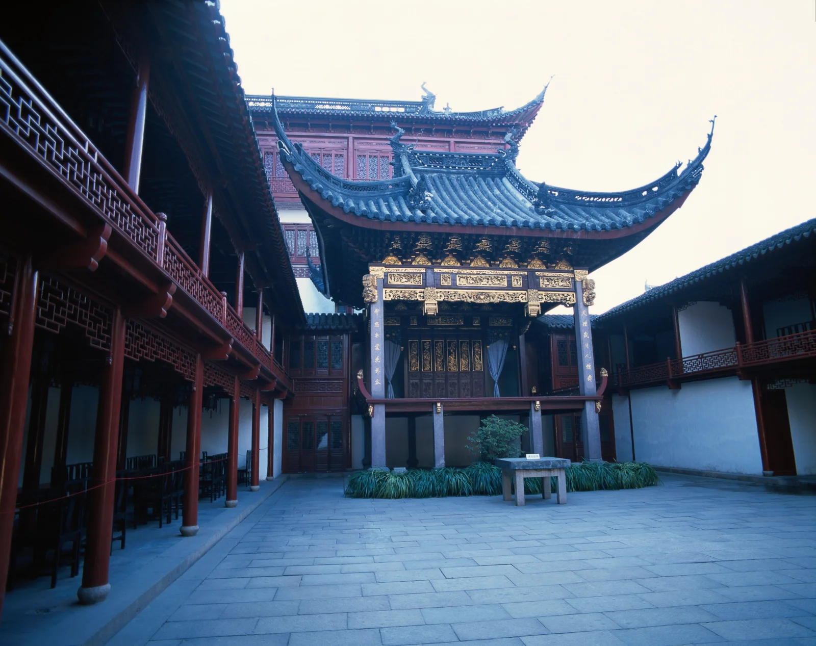 一座传统中式建筑围合的庭院中央矗立着装饰华丽的木结构门楼。