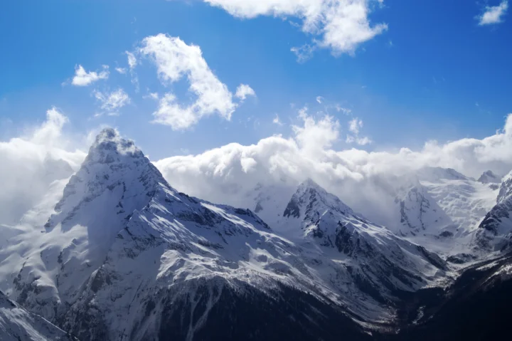 巍峨的雪山在蓝天和厚重云层映衬下延展开来。