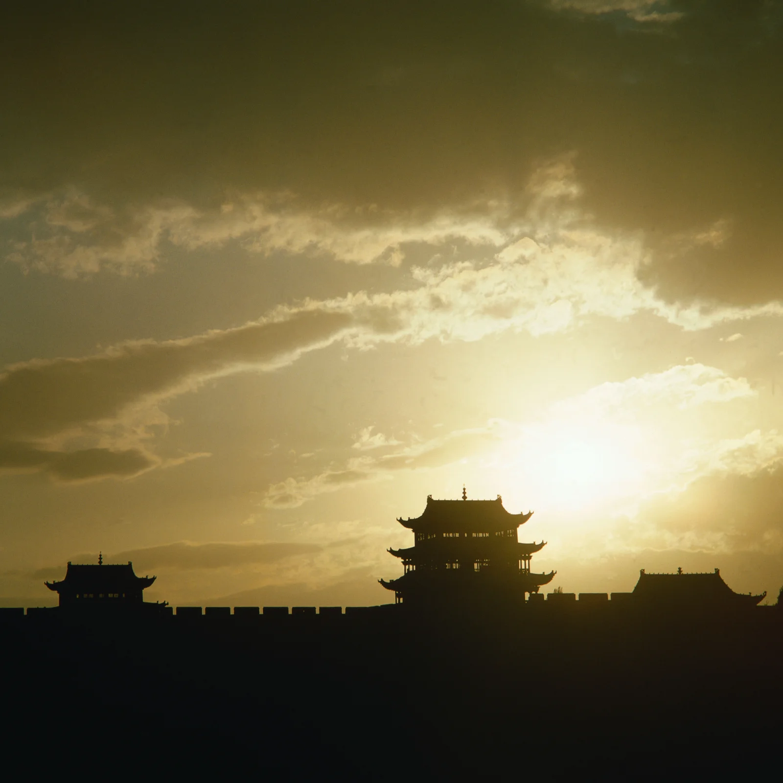 夕阳映照下，一座古建筑群呈现出深色剪影。