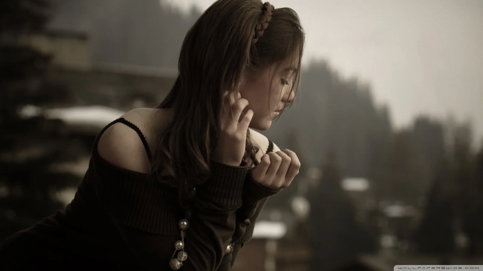 어두운 옷을 입은 여성이 빛을 향해 돌아서 있고 뒤에는 부드럽게 흐려진 도시 배경이 보입니다.
