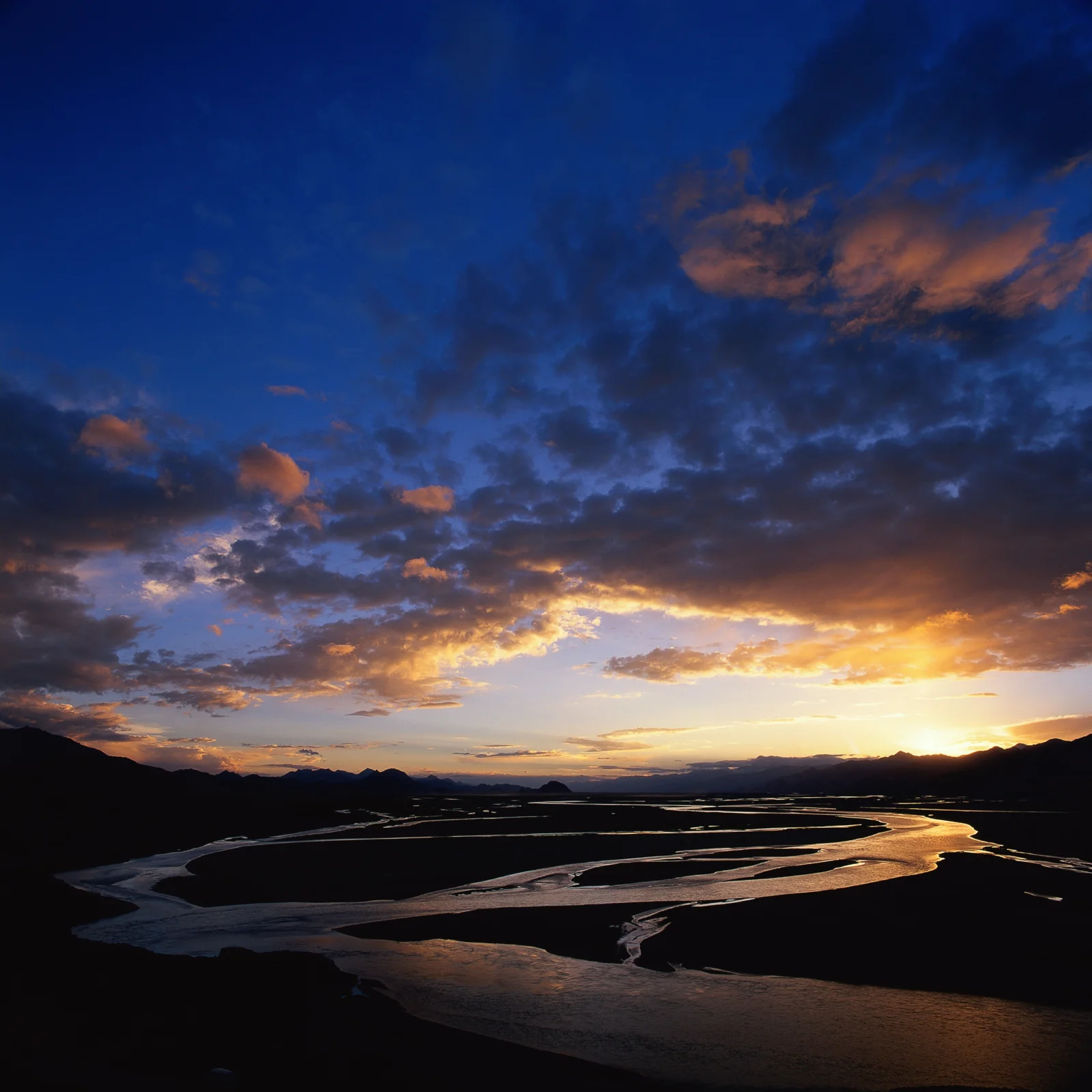 夕阳映照着蜿蜒河流、远山和层叠云彩。