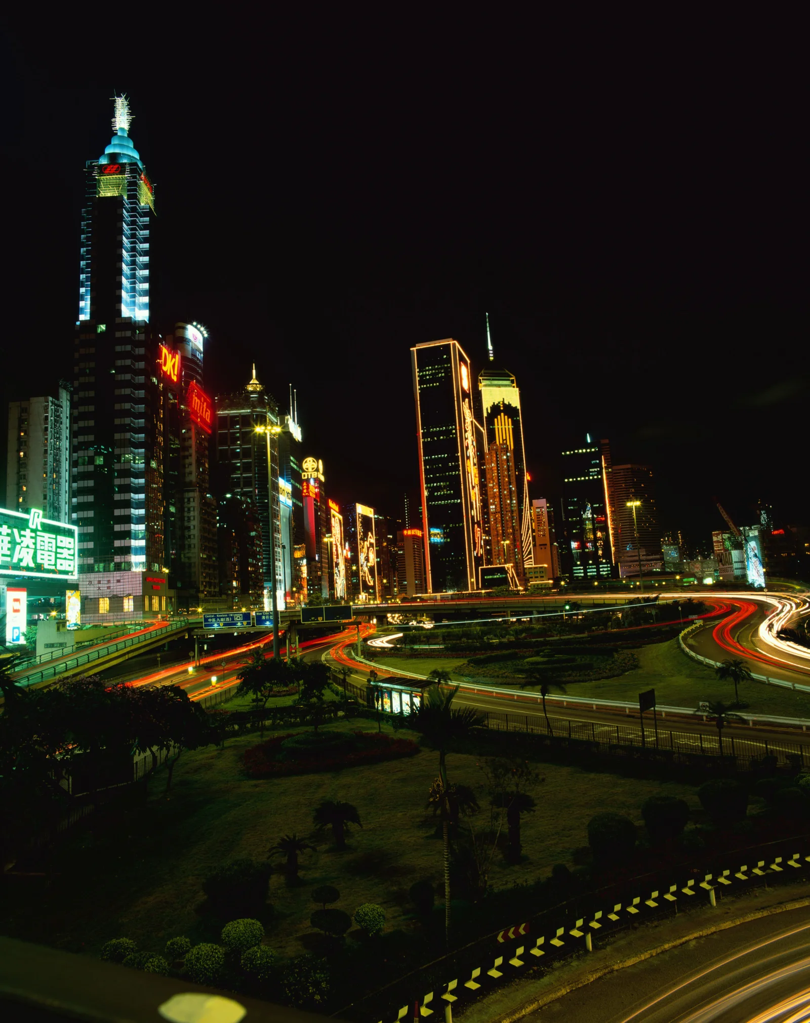 夜晚高楼与霓虹灯环绕着车流交织的城市高架道路。