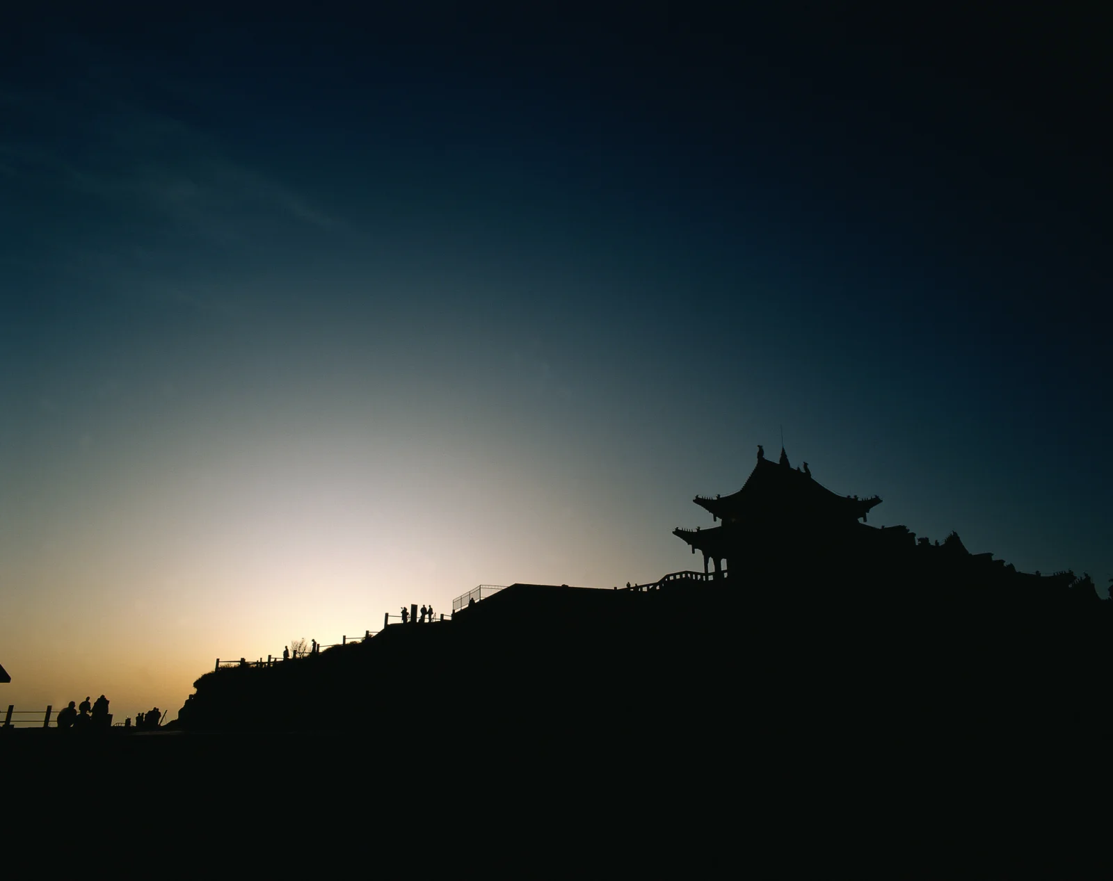 夕阳映照下，山脊上的古建筑呈现出深色剪影。