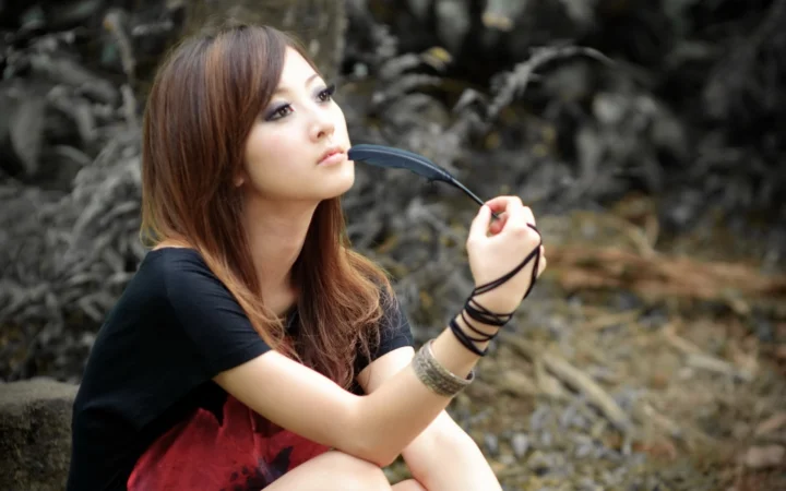 成人女性が森の中でサングラスを手にしてポートレート撮影をしている。