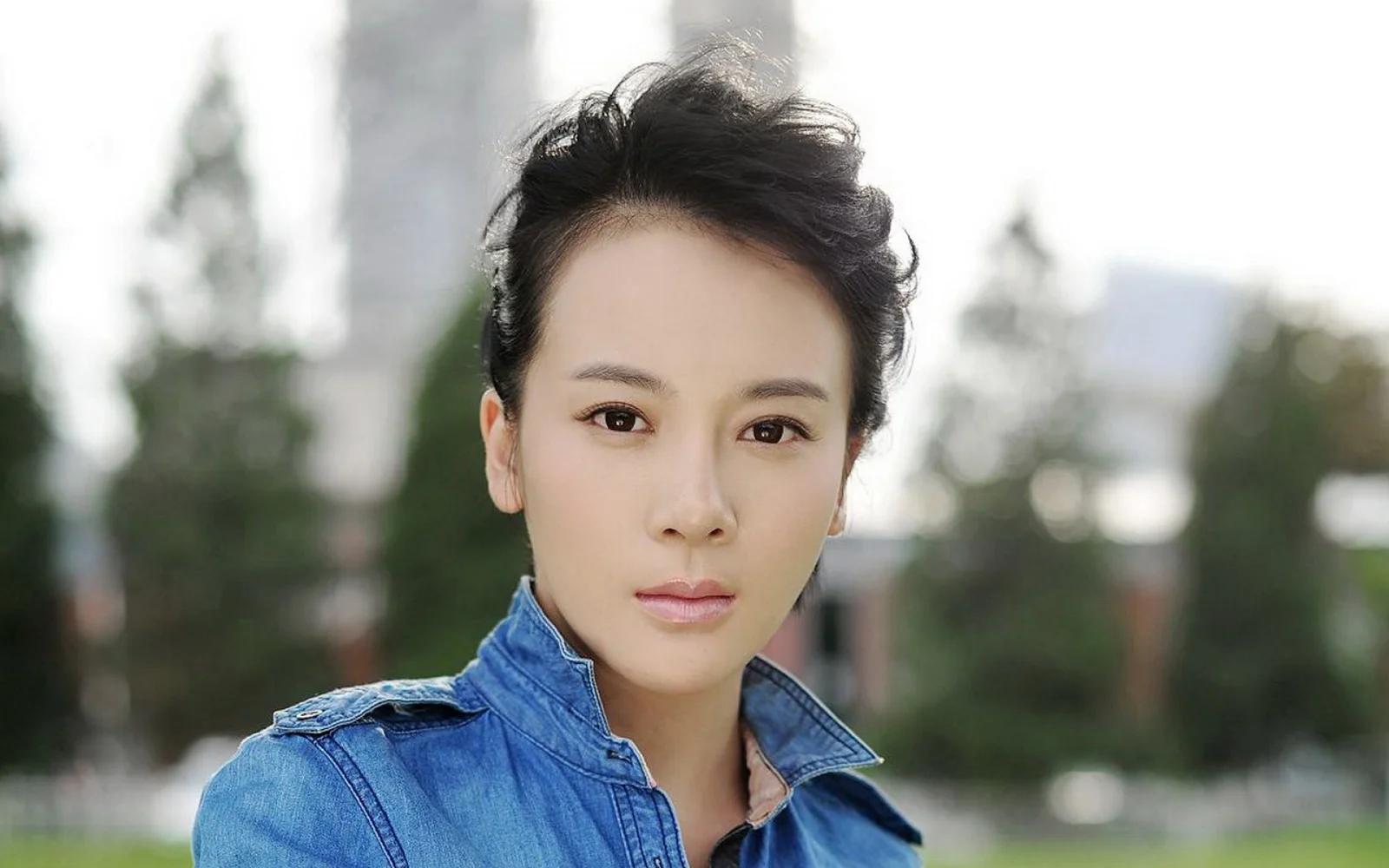 一名身穿蓝色夹克的女性在户外背景前面向镜头。