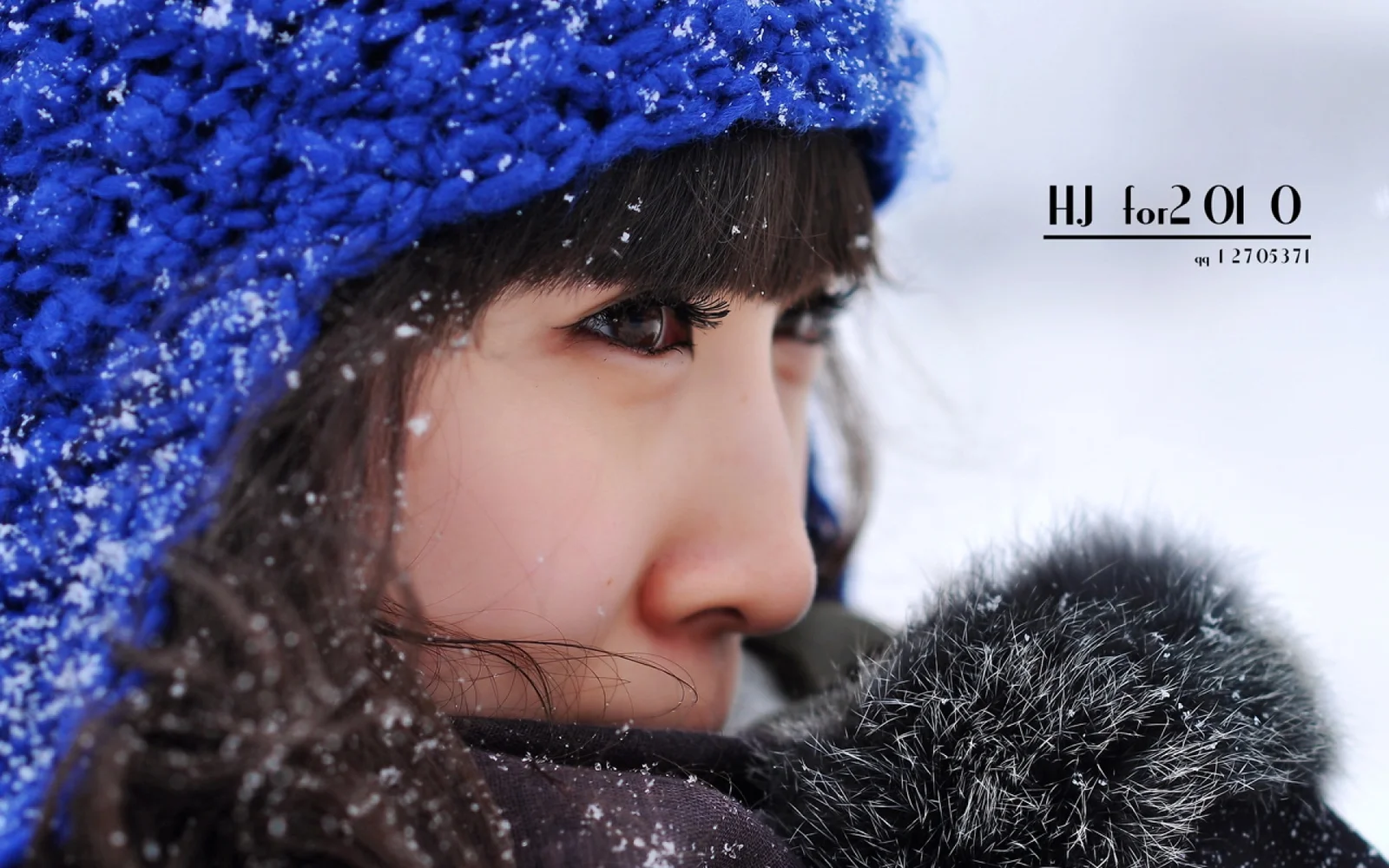 一位戴着蓝色针织帽的女性在飘雪中侧脸近景入镜。