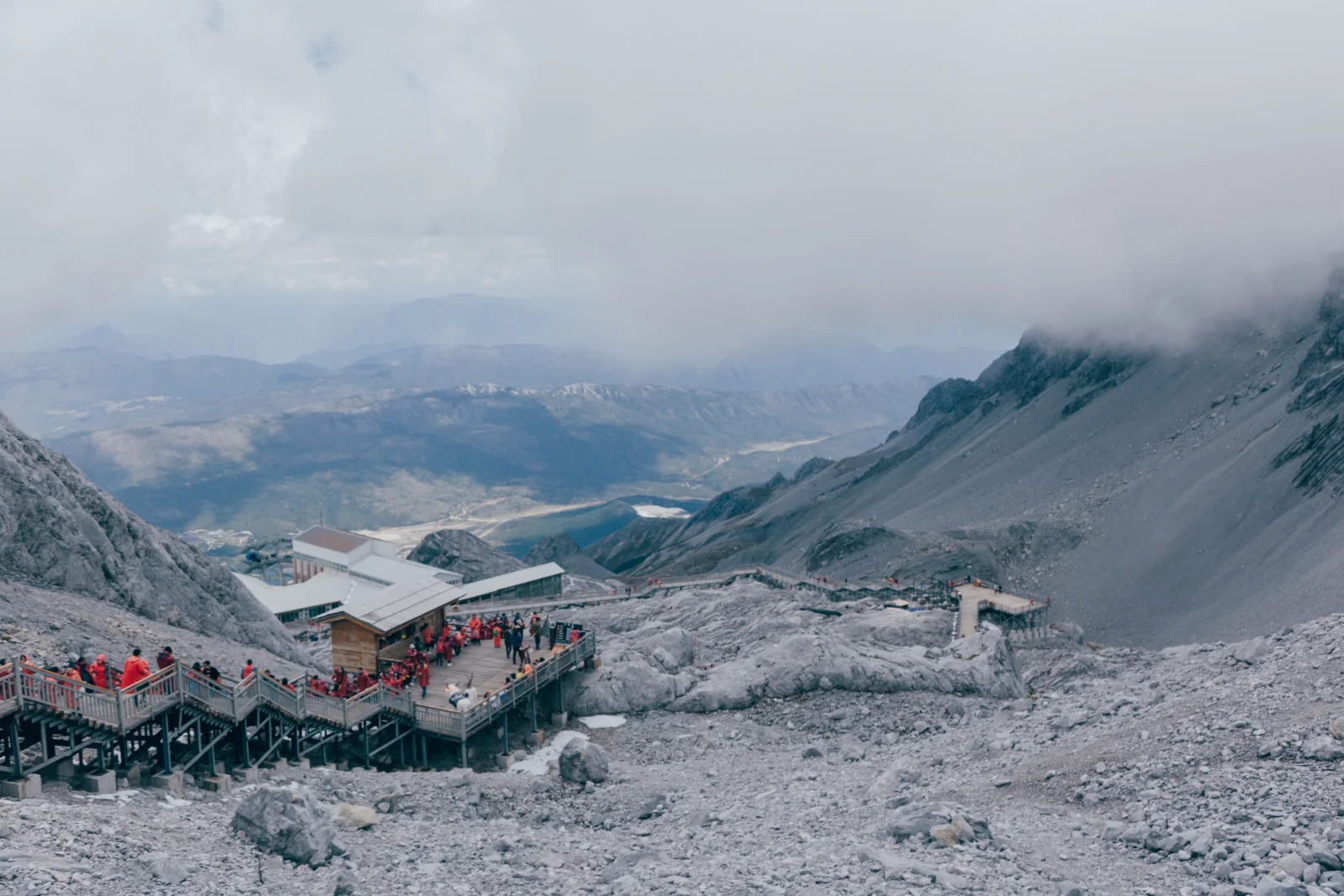 云雾笼罩的高山岩坡延伸至远方，山间设有观景平台和栈道。