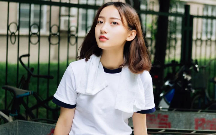 一名身穿白色上衣的女子站在户外围栏前。