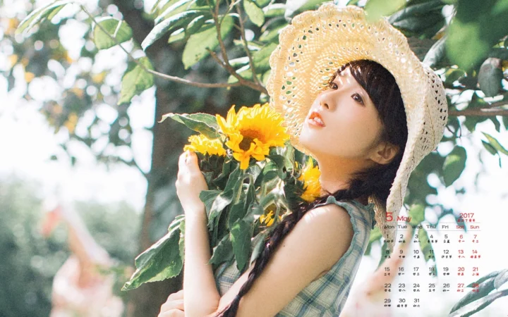 一名戴草帽的成年女性在绿叶和向日葵间侧身望向镜头。