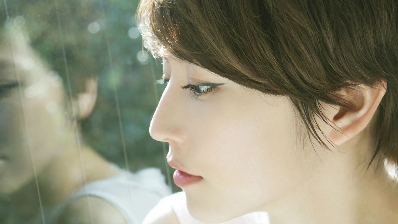 一位成年女性的侧脸近距离人像，阳光从侧面照亮她的面容。