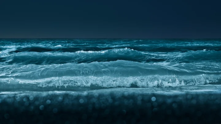 深蓝色海面上层层白色浪花向岸边翻涌。
