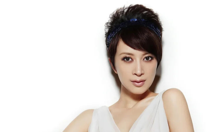 一名戴着深色发带的女性在白色背景前面向镜头。