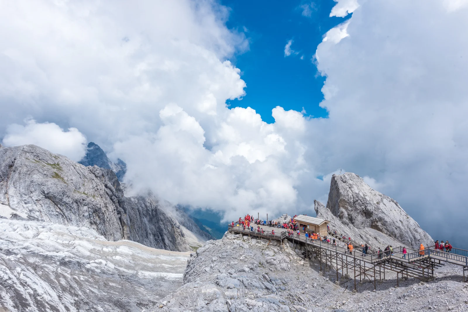 雪山と厚い雲、山中の遊歩道が壮大な高山風景を形作っている。