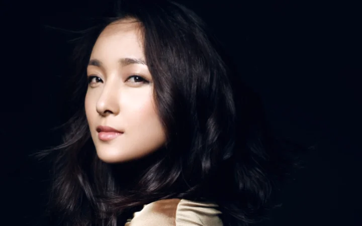 一位黑发女性在深色背景前进行近距离肖像拍摄。