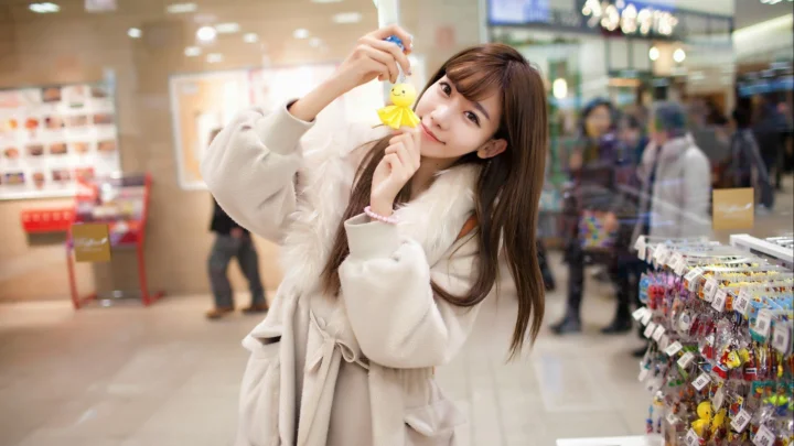 一名女性在商店内手持黄色小玩具面对镜头。