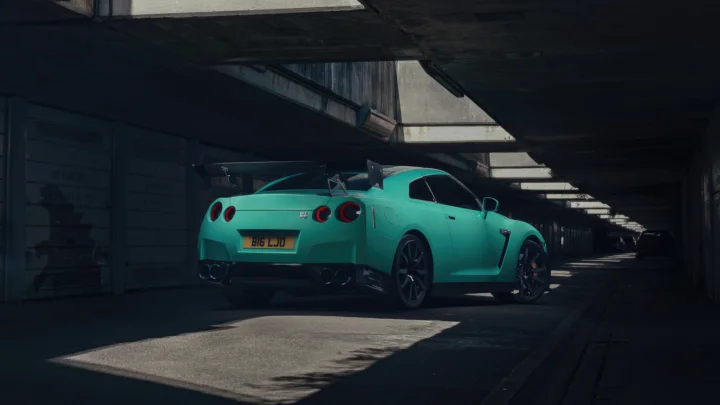 一辆绿色跑车停在光影交错的地下车库通道中。