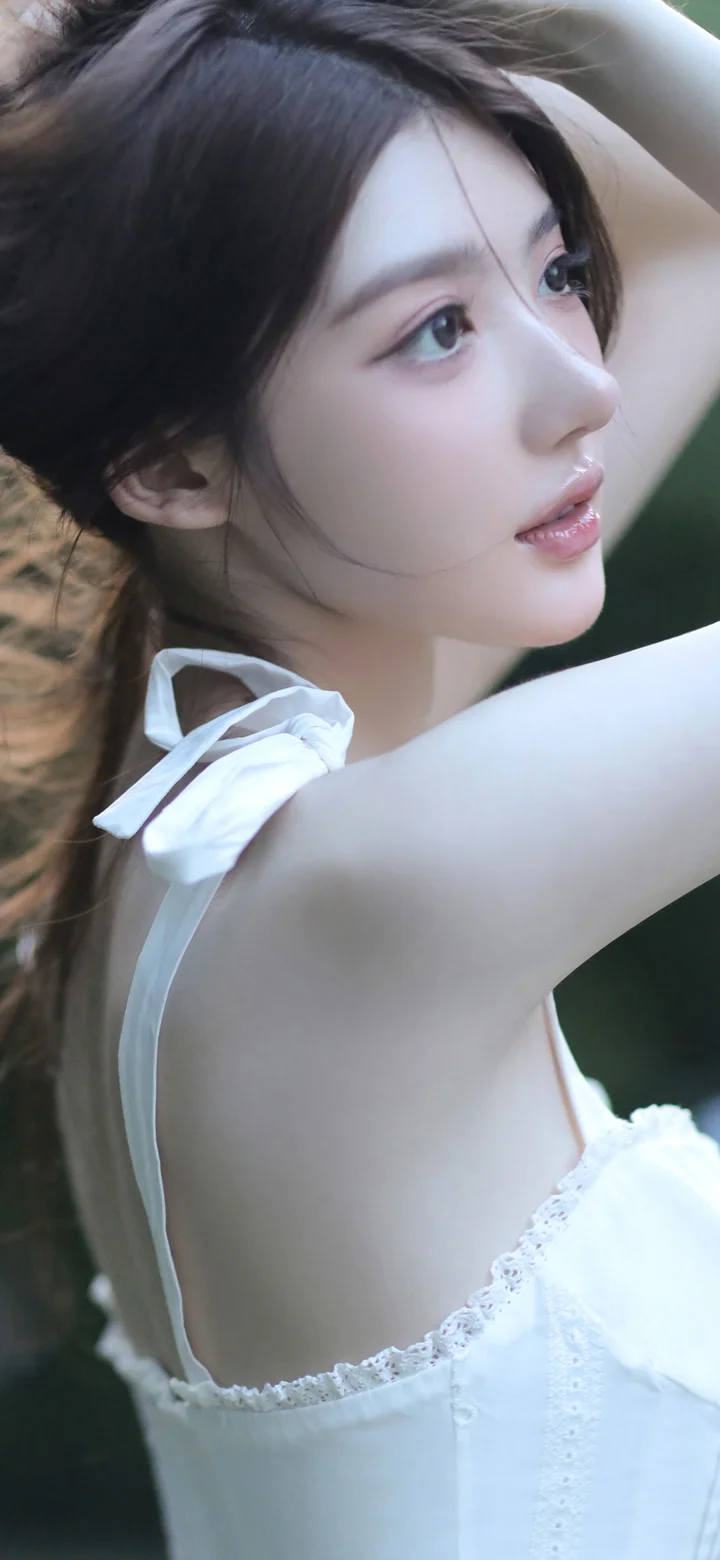 一名成年女性身穿白色服装，抬臂侧身面对镜头。