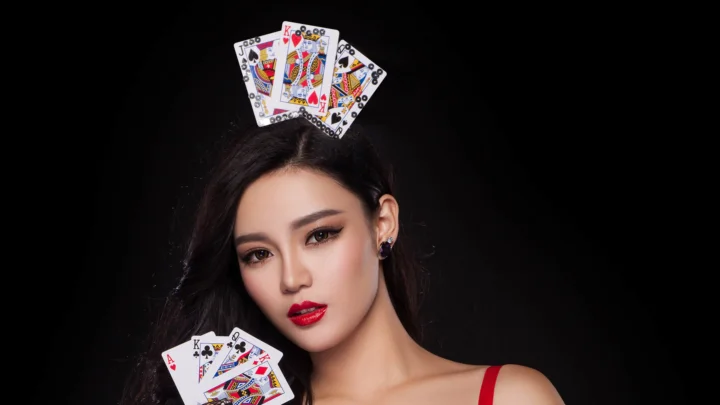 黑色背景前，一名女性头戴并手持扑克牌面对镜头。
