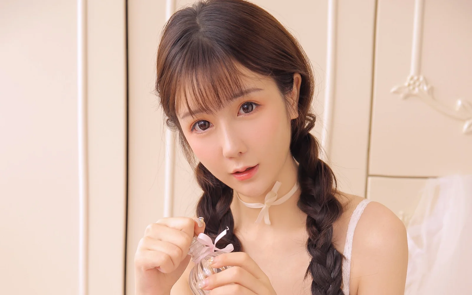 一位留着双辫的女性在暖色室内对着镜头微笑。