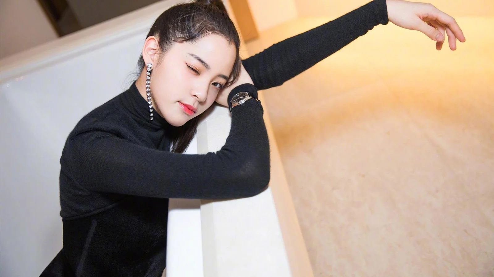 一名身穿黑色上衣的女性在室内摆出姿势。