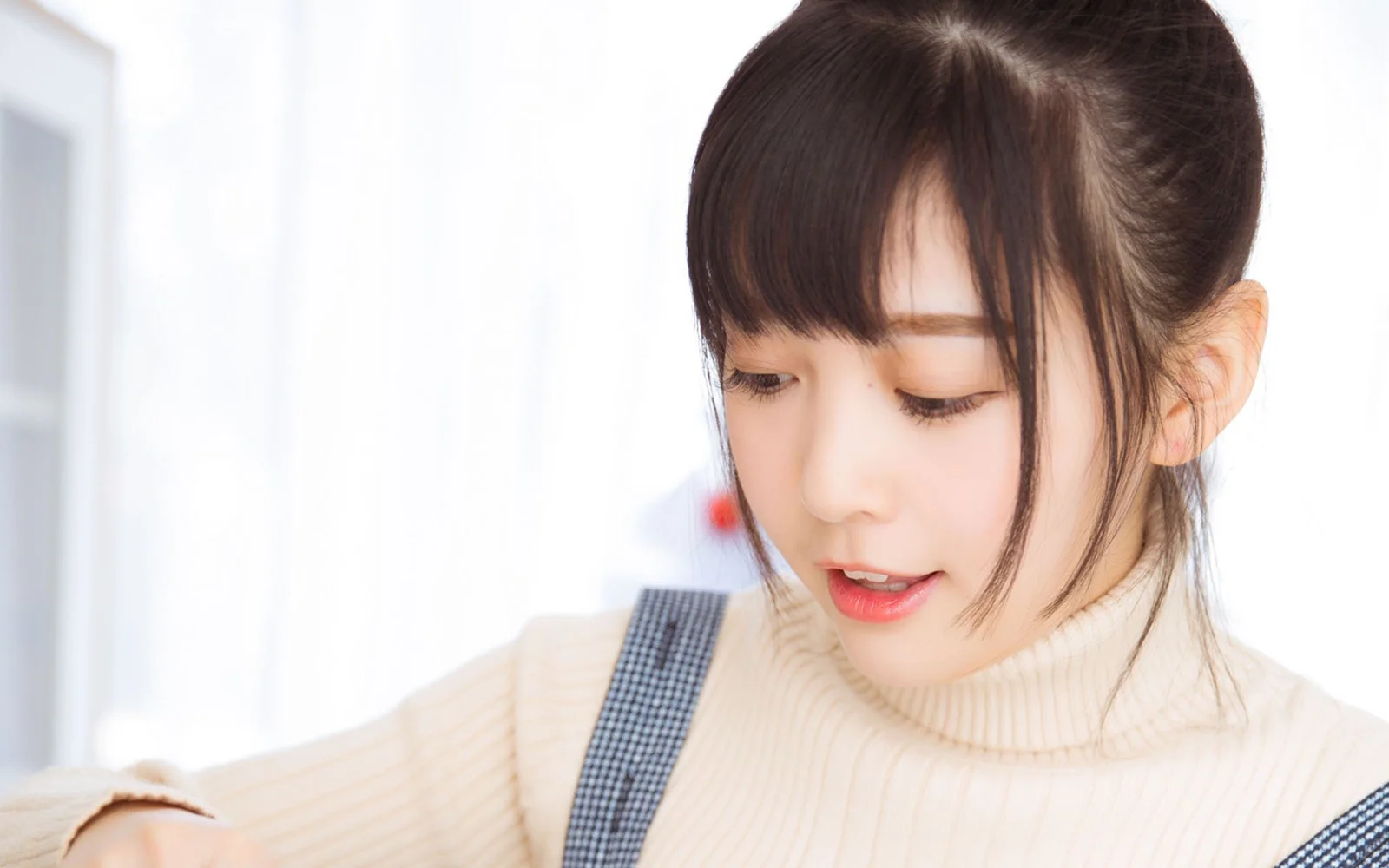 一位穿着奶油色高领毛衣的女性低头看向画面下方。