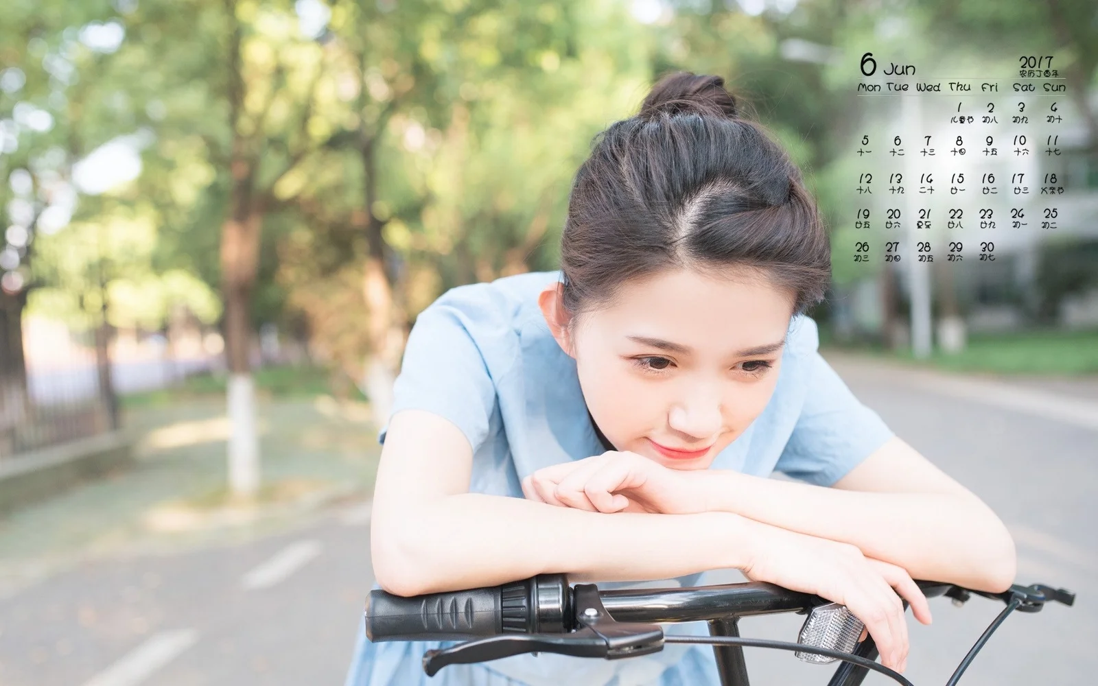 나무가 늘어선 길에서 한 여성이 자전거 핸들에 몸을 기대고 있습니다.