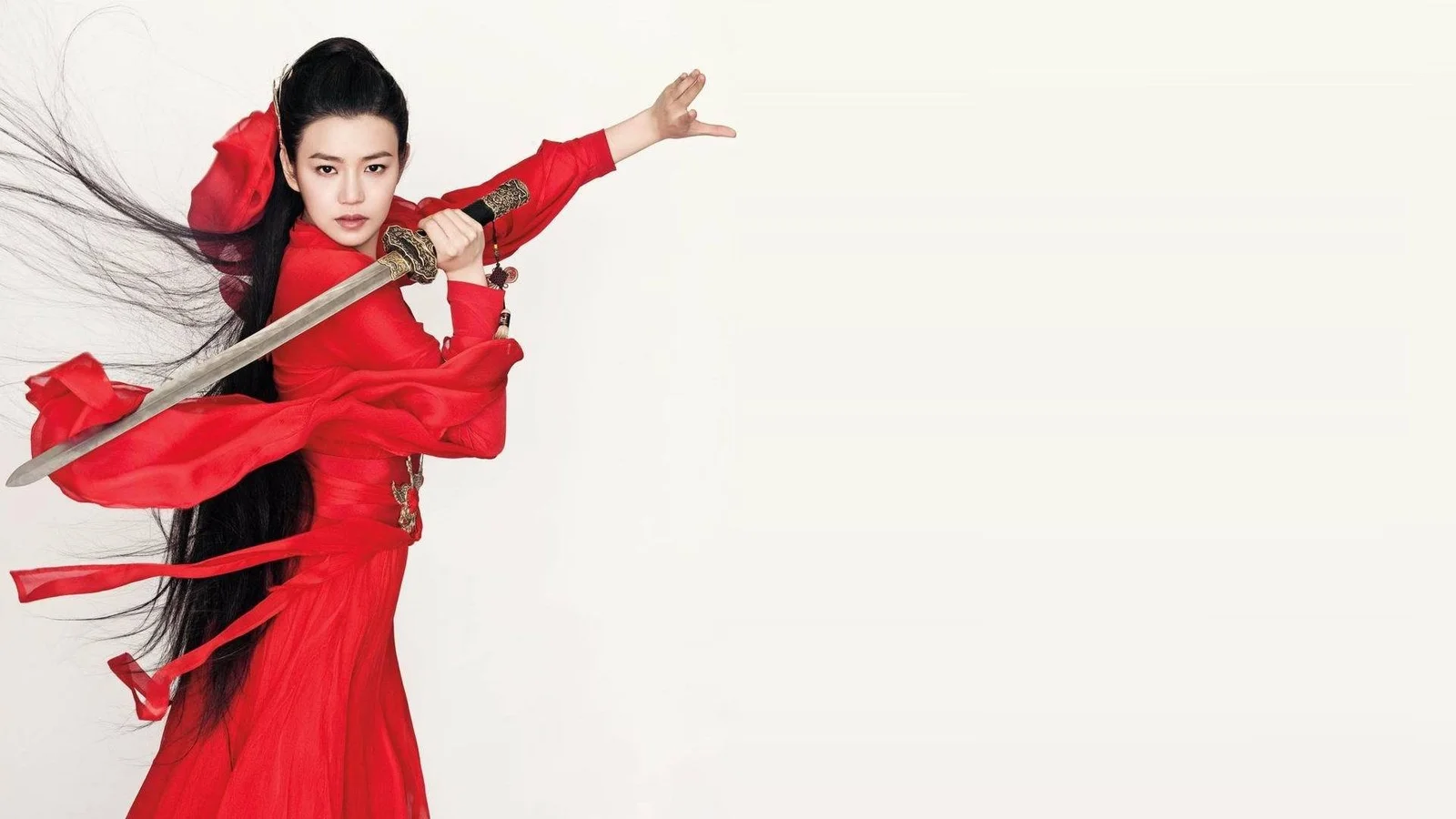 一名身穿红色服装、手持长剑的女性站在白色背景前。
