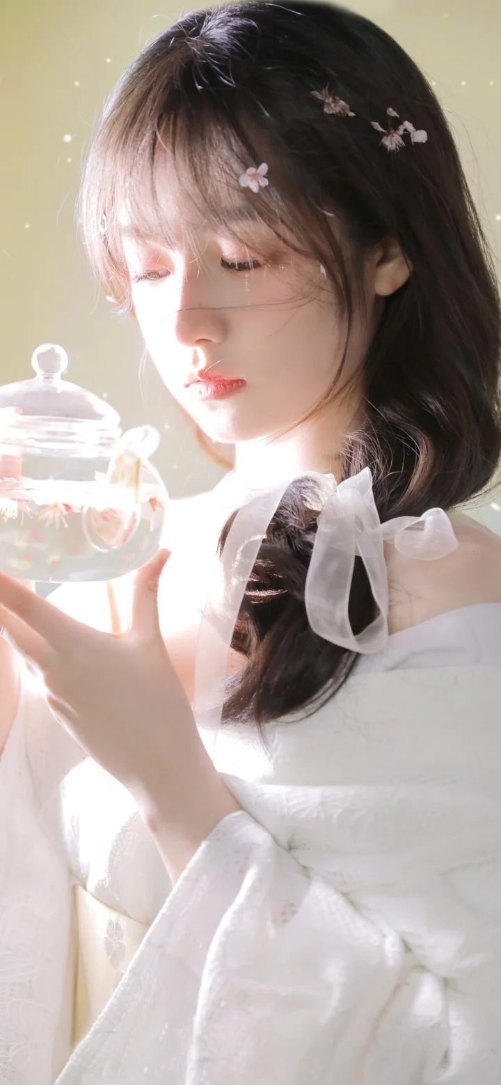 一位长发女性身穿白色连衣裙，手持透明玻璃罐，柔和光线映照着她的侧脸。