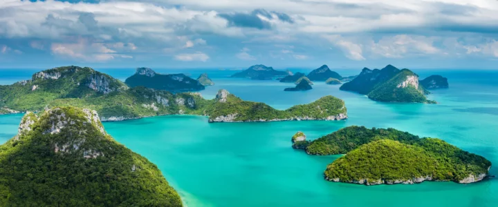 碧蓝海水环绕着层叠的绿色岛屿与山峦，天空中飘着云朵。