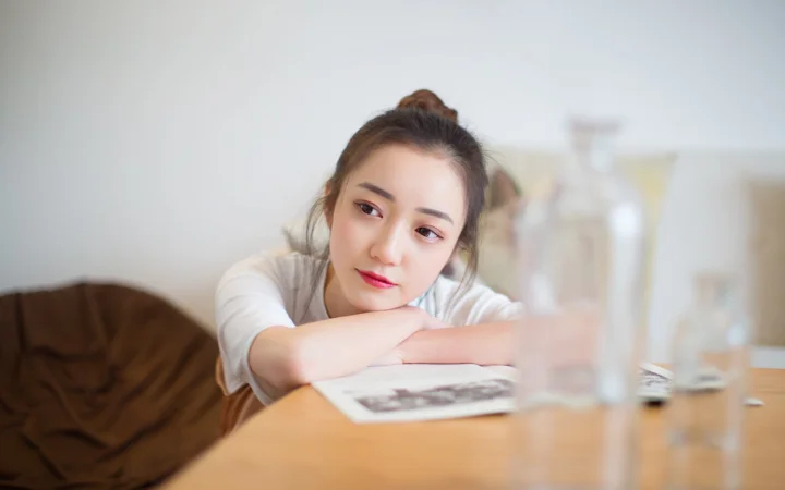 한 여성이 테이블에 팔을 올리고 조용히 앞을 바라보고 있습니다.
