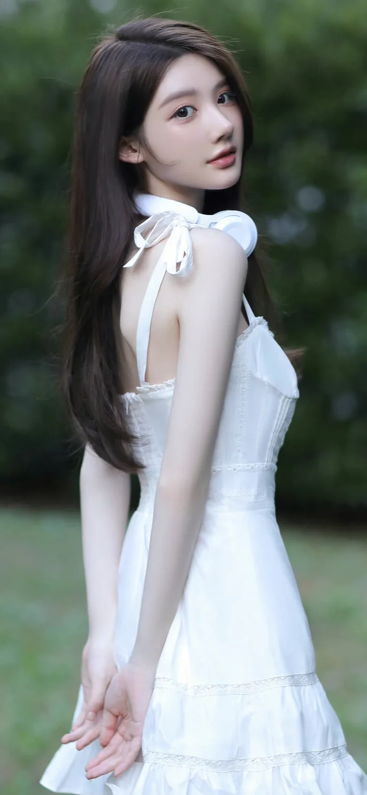 一名長髮女子穿著白色連身裙在戶外回眸。