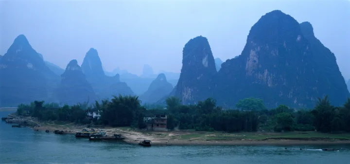 群山、河流与岸边植被共同构成一幅宁静的自然风景。