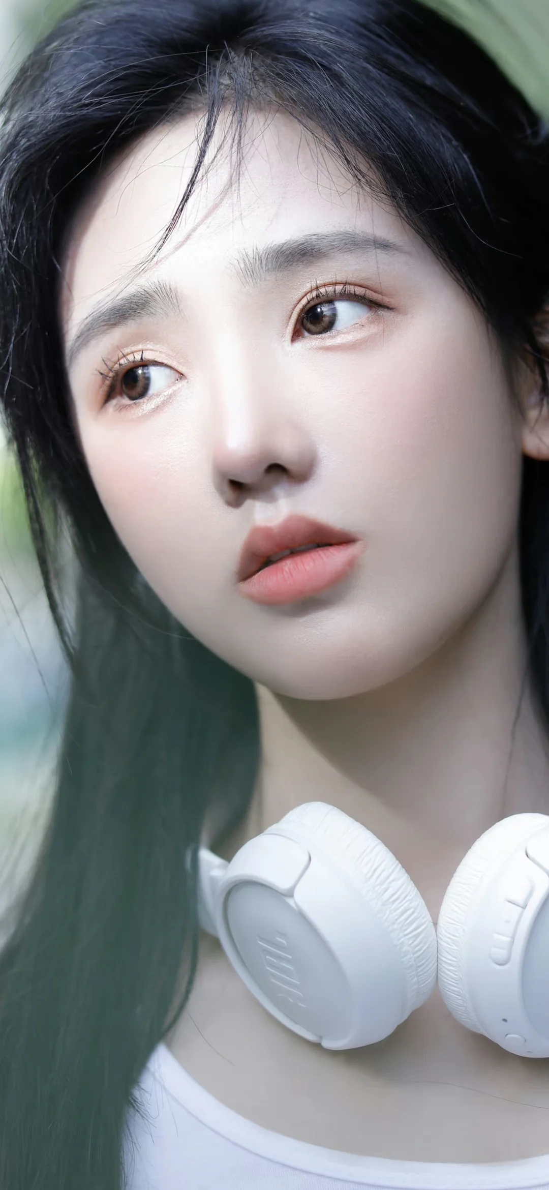 一位黑发女性佩戴白色头戴式耳机的近距离肖像。