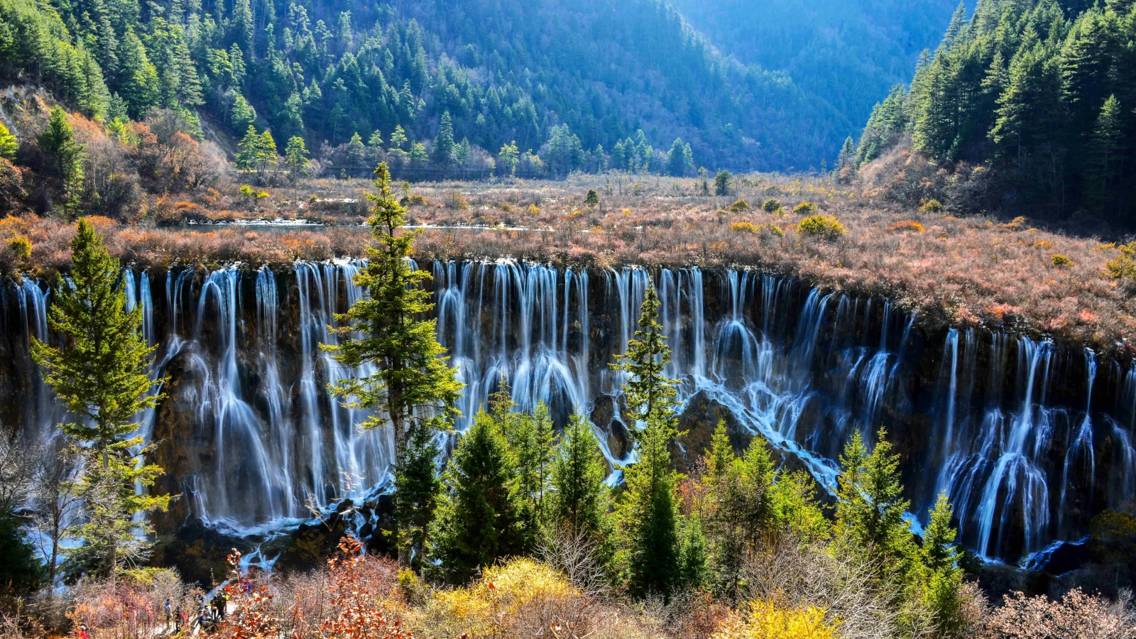 群山森林之间的瀑布从岩壁上倾泻而下。