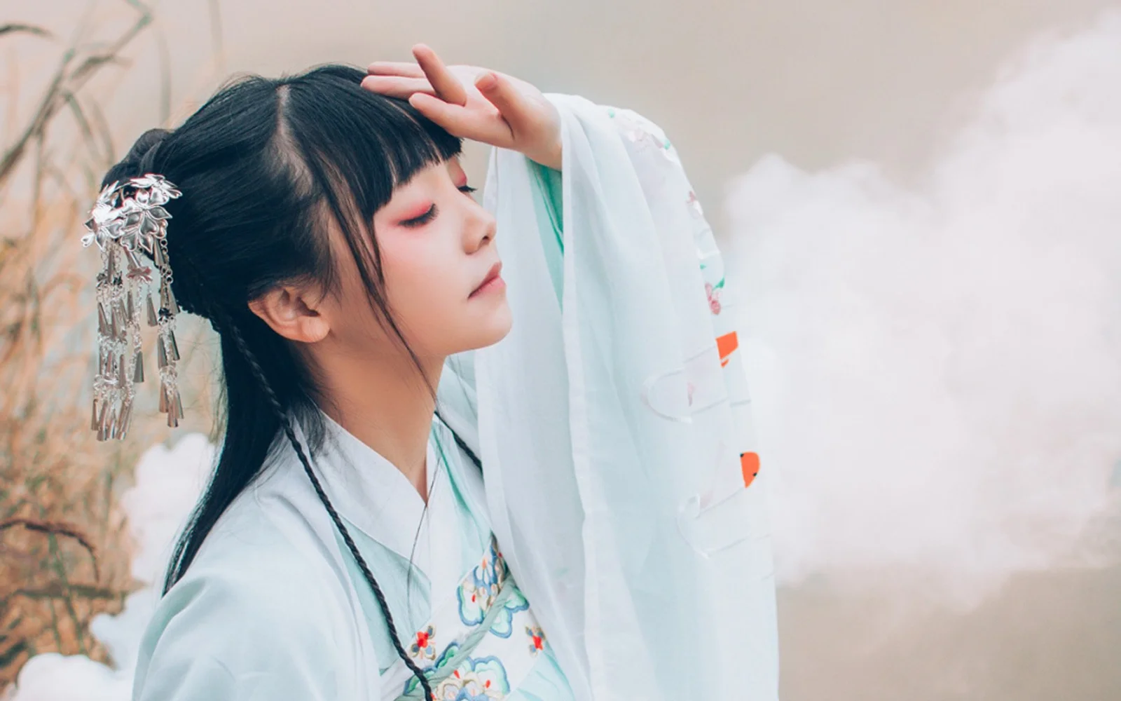 一名身穿白色传统服饰、佩戴发饰的女性侧身抬手遮光，背景朦胧明亮。